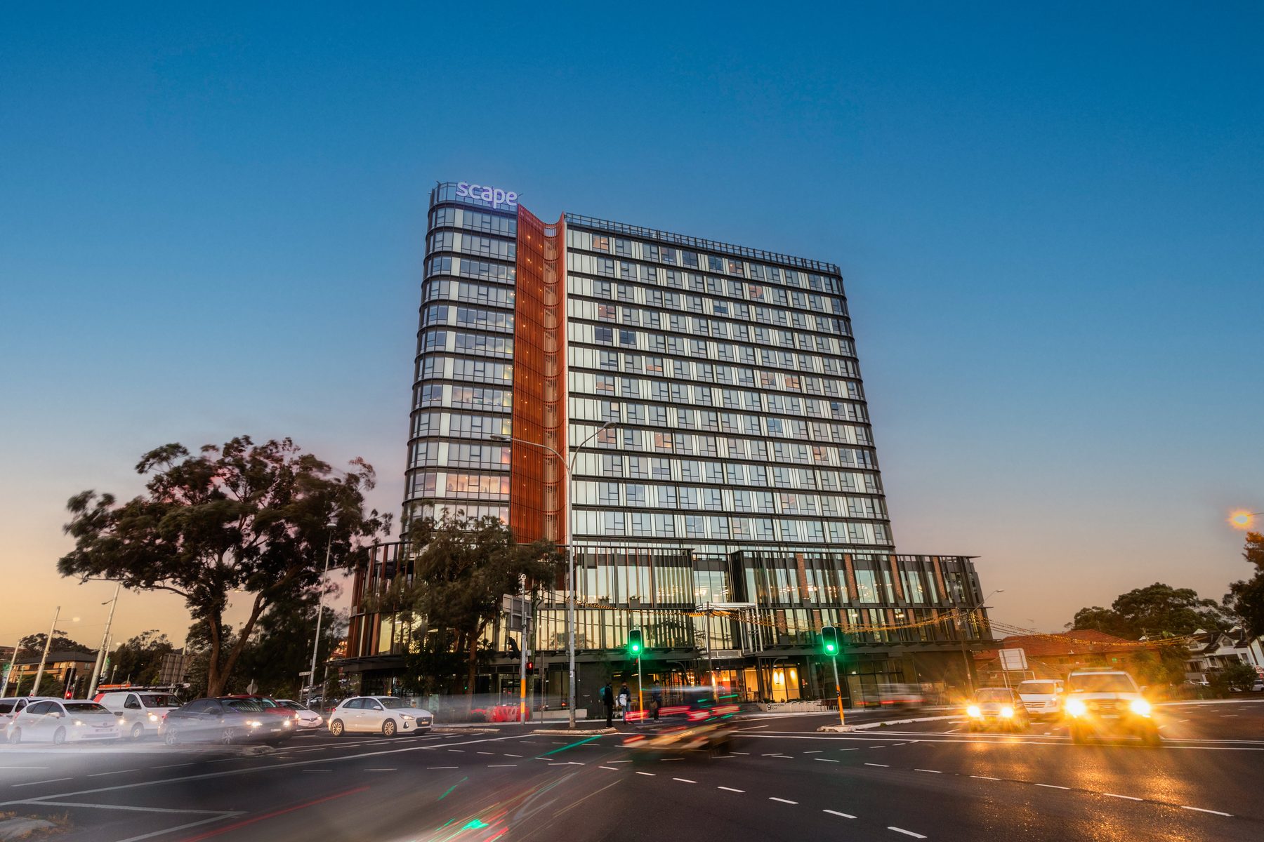 Blue hour exterior of a high-rise student accommodation tower with light trails