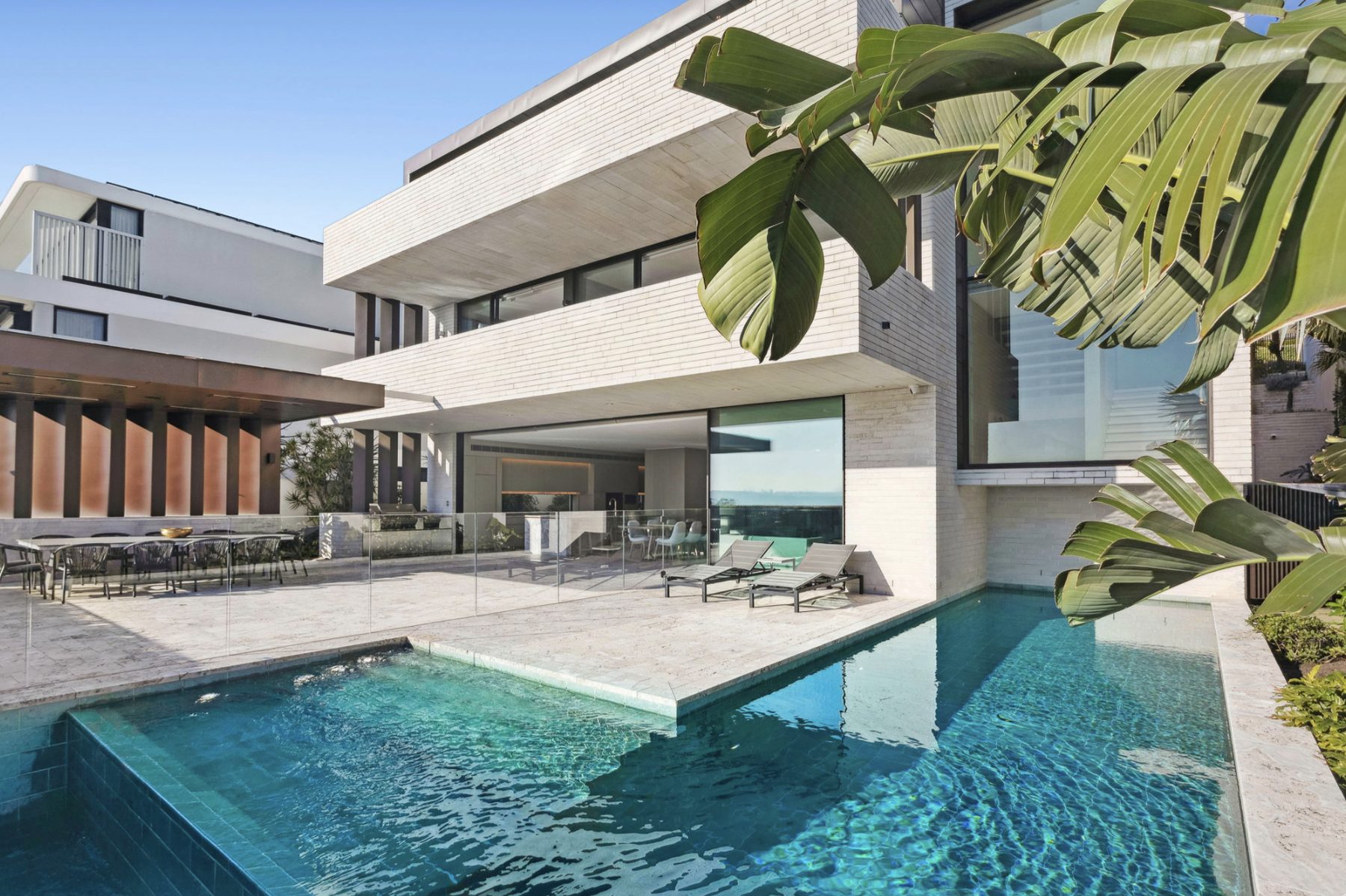 White brick residence exterior with pool and outdoor dining terrace