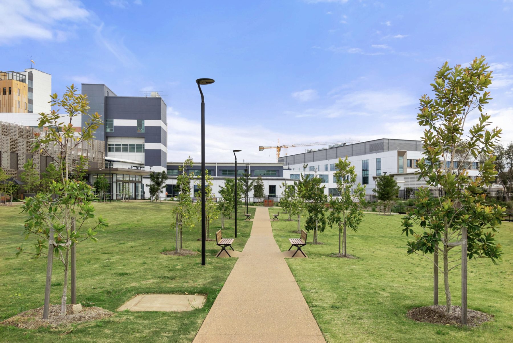 Wide view of hospital campus buildings with landscaped park and pathway