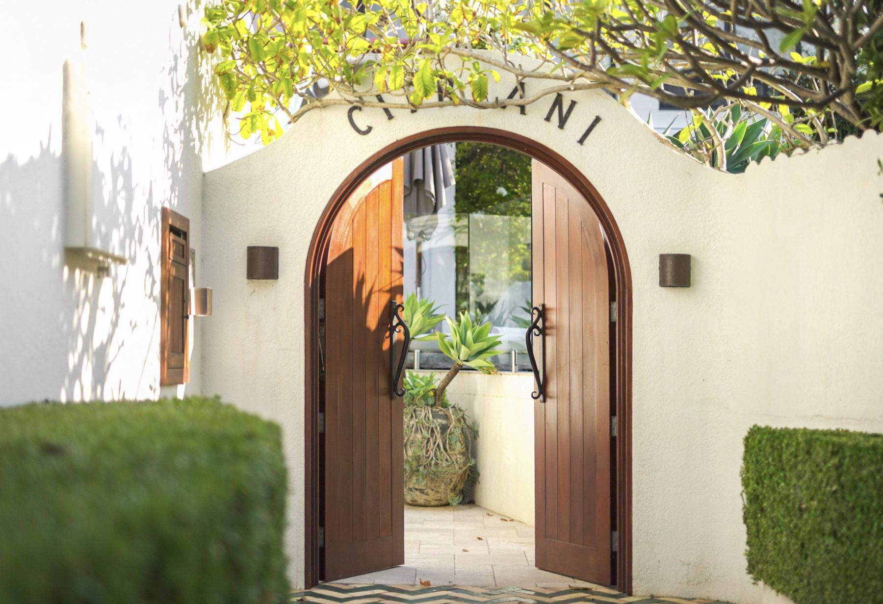 Arched wooden entrance gate detail framed by greenery