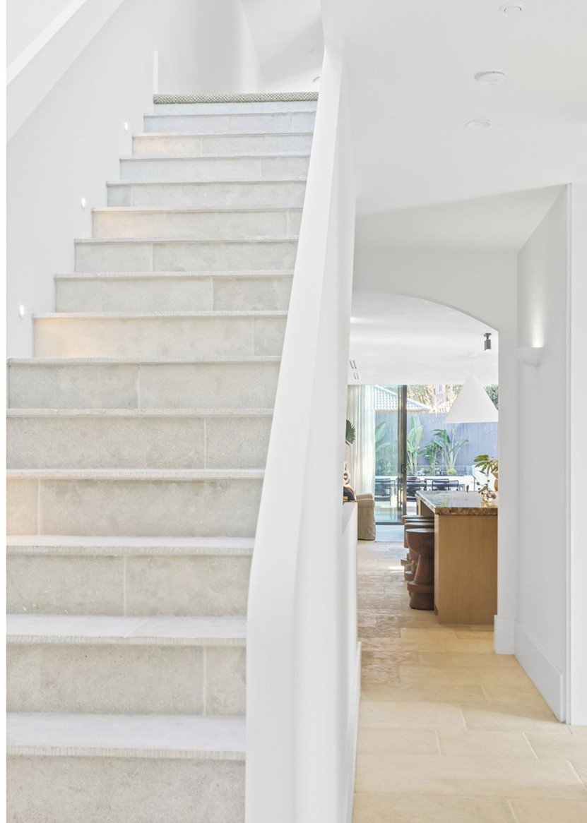 Curved stone staircase leading down to an open plan kitchen and pool view