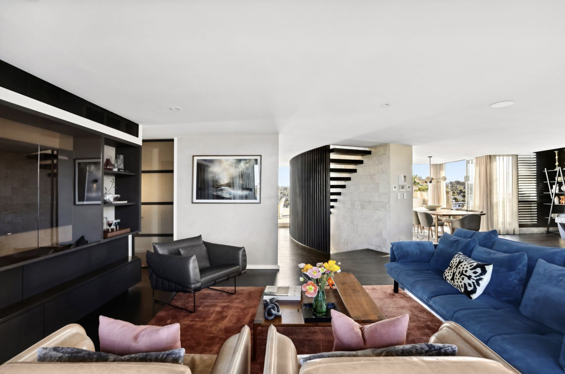Living room styled with a blue sofa and sculptural staircase