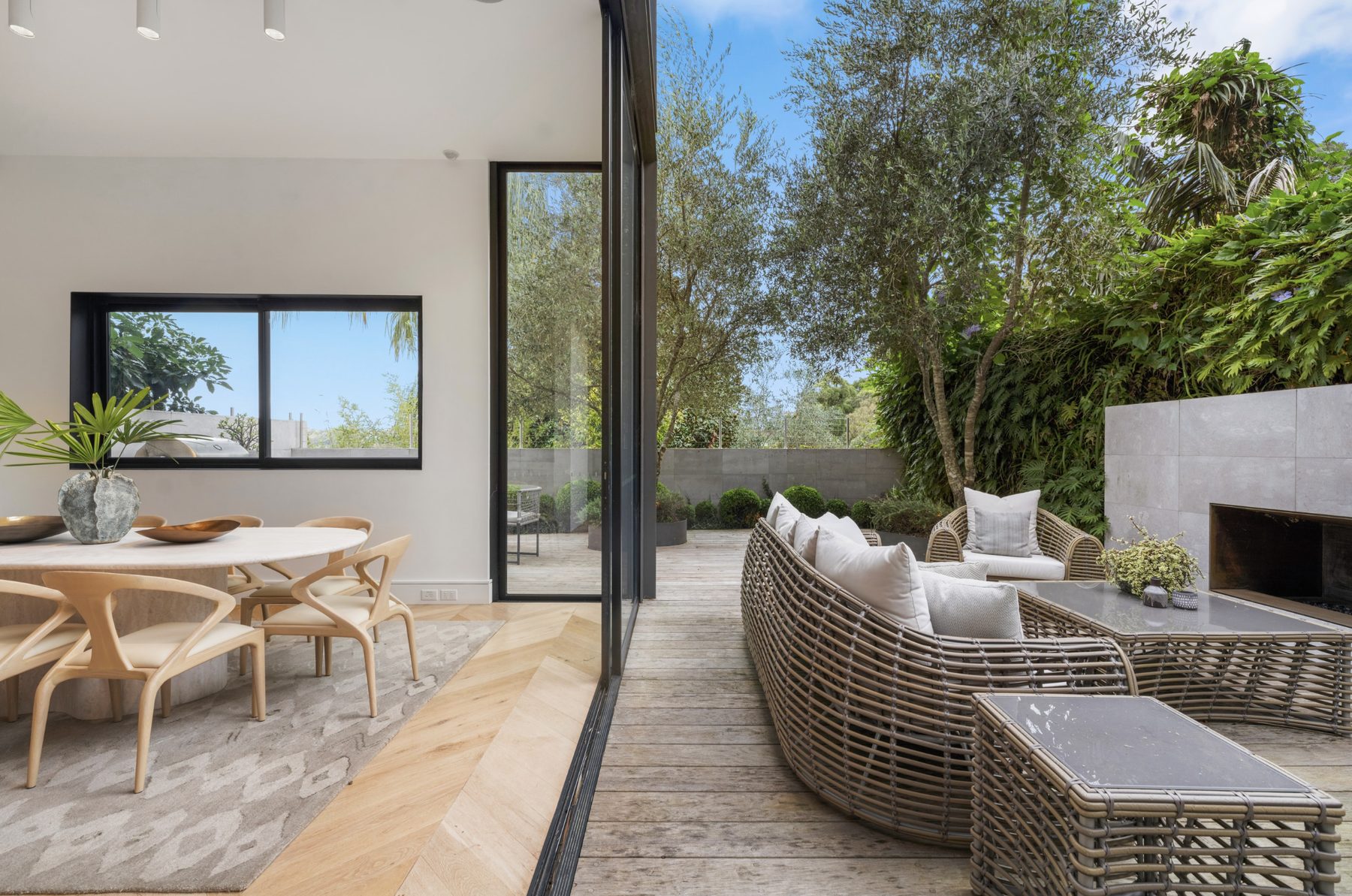 Dining room opening onto an outdoor rattan lounge and fireplace