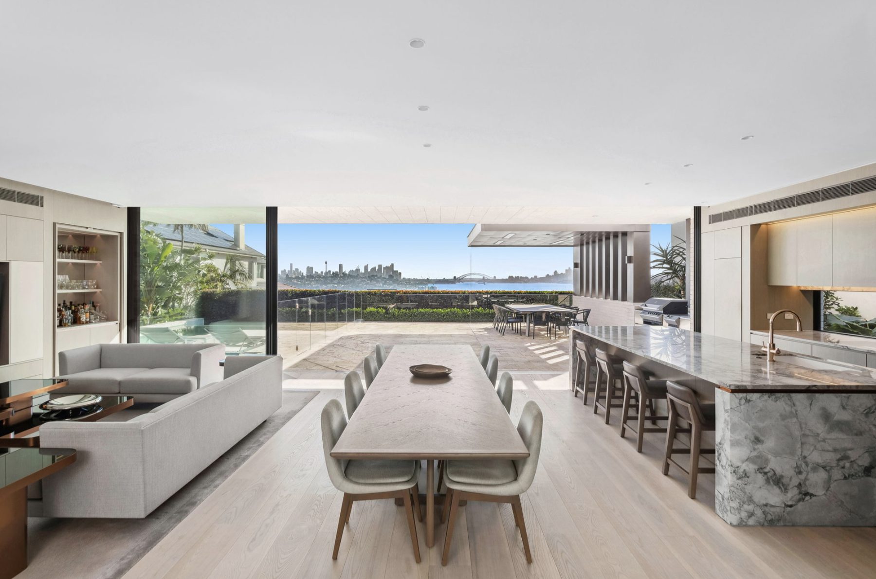 Open plan dining, kitchen and pool with city skyline and harbour bridge view