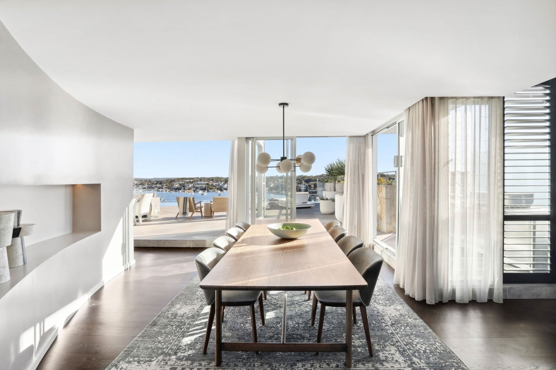 Dining room open to a curved living room with marina and harbour views